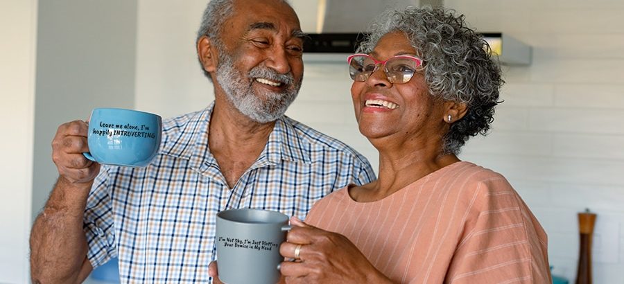 Happy african american senior couple holding mugs with coffee and talking. healthy retirement lifestyle at home.